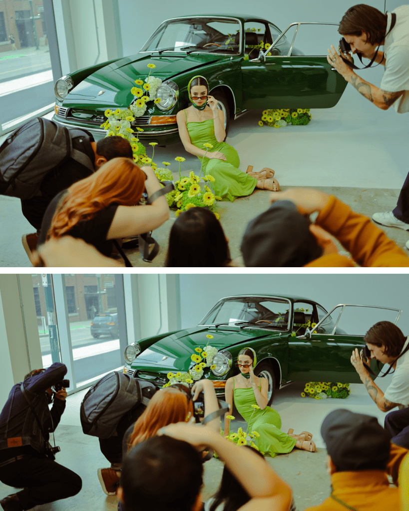 A model in a green dress poses with a vintage green car surrounded by yellow flowers, while photographers capture the scene.